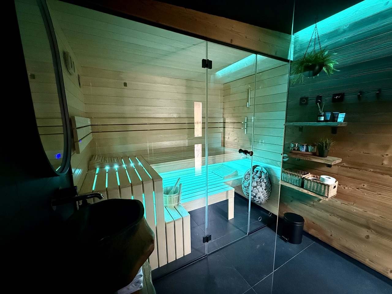 Prosklená finská sauna nasvícená tyrkysovým světlem